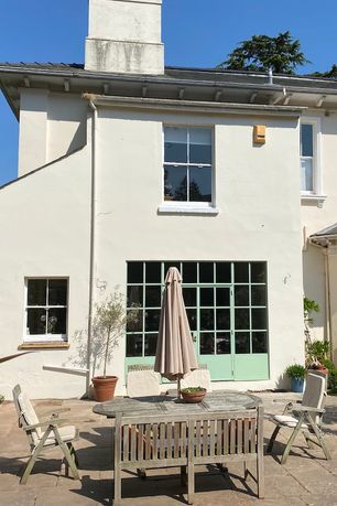 The rear of the house, with green french doors leading onto a patio and a dining area