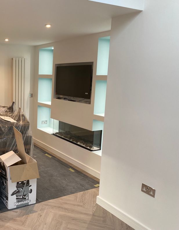 A tv media wall with modern white cubicles and a fish tank below the wall mounted tv